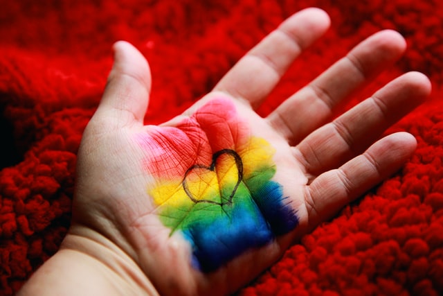casais gays se conheceram online - mão com um coração com as cores do arco-íris