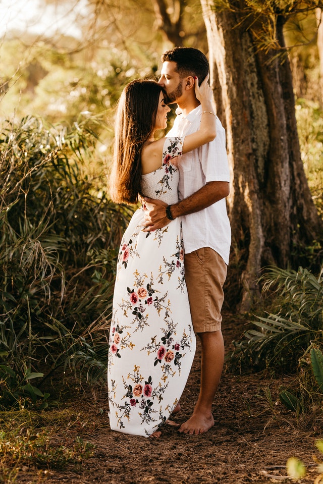atitudes para fazer o amor crescer: casal se abraçando apoiado em uma árvore, ao pôr do sol