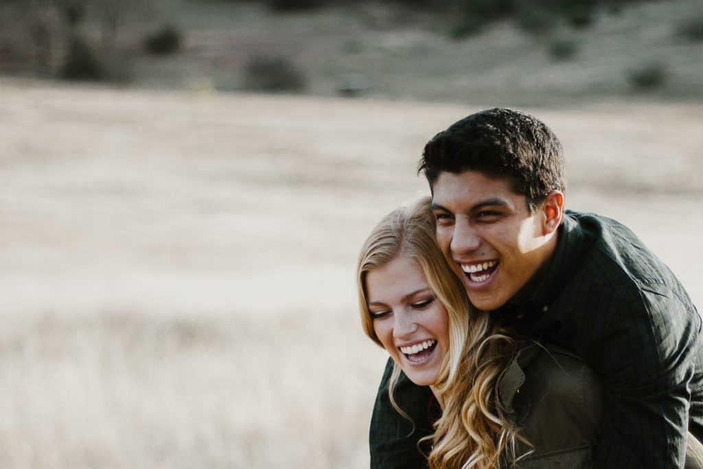 como conquistar uma mulher: mulher sorrindo carregando homem no cangote