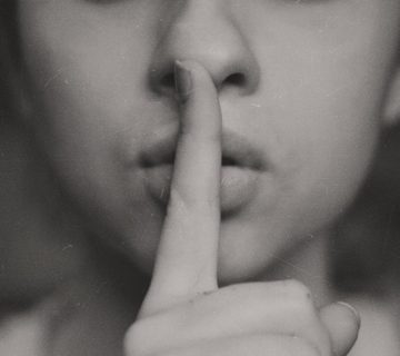 site de traição: foto preto e branco de uma mulher com o dedo sobre a boca, indicando segredo