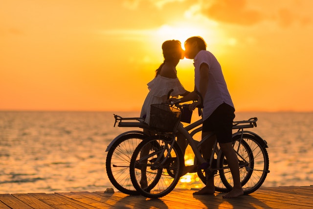 como arrumar um namorado: casal de bicicleta se beijando ao por do sol