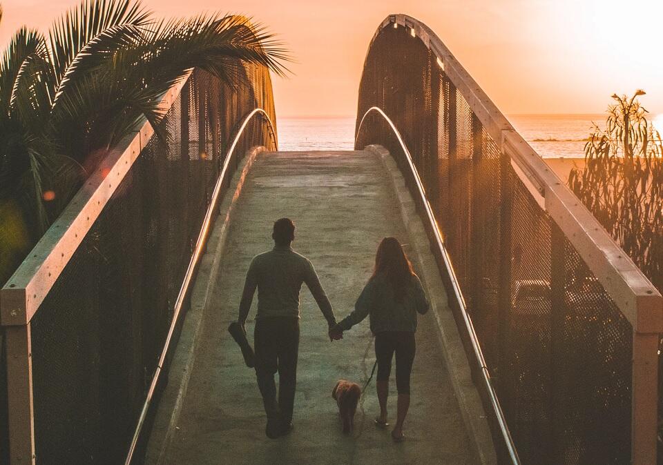 como reconquistar o ex: casal de mãos dadas subindo ponte ao pôr do sol