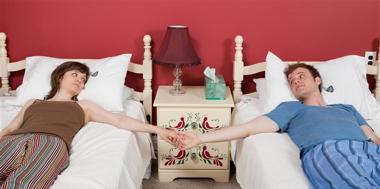 Casal dormir separado: casal no mesmo quarto, de mãos dadas, mas cada um em sua cama