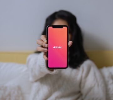 bio para tinder: mulher mostrando o celular com a tela do aplicativo Tinder